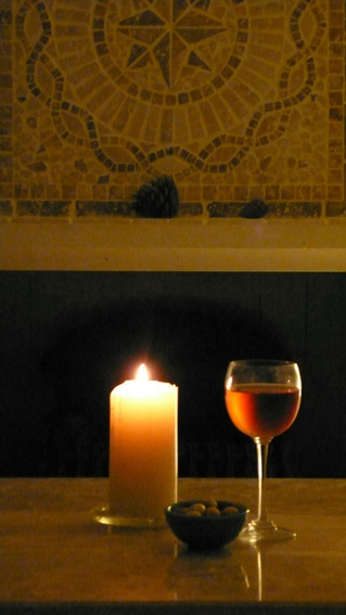 Glass of wine and candlelight by fireplace
