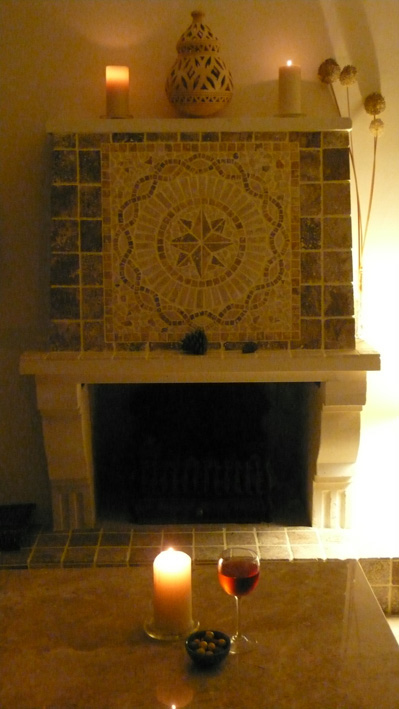 Glass of wine and candlelight by mosaic tiled fireplace
