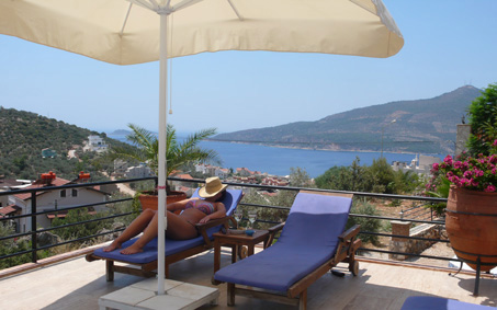 Relaxing on sun lounger by the pool with Kalamar Bay view in the background